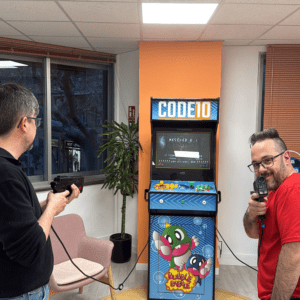 Code10 team members enjoying a retro arcade game in the office recreation area, reflecting the company's collaborative culture, team spirit and work-life balance.