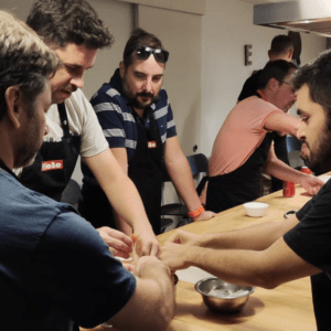 Code10 employees collaborating during a cooking workshop as part of a company team-building activity, preparing dishes together in a professional kitchen.