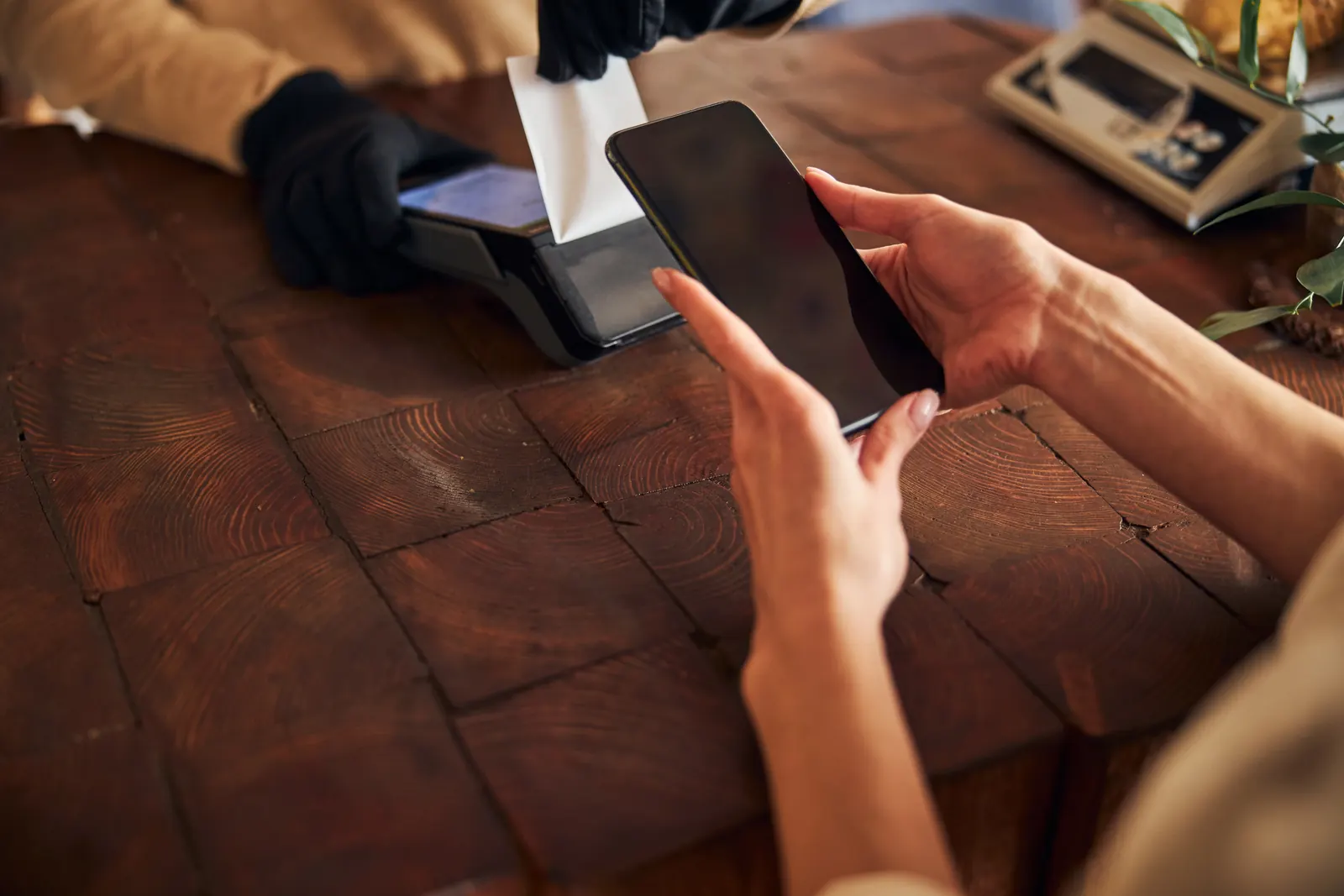 Un cliente que paga sin contacto con un smartphone en la barra de una cafetería