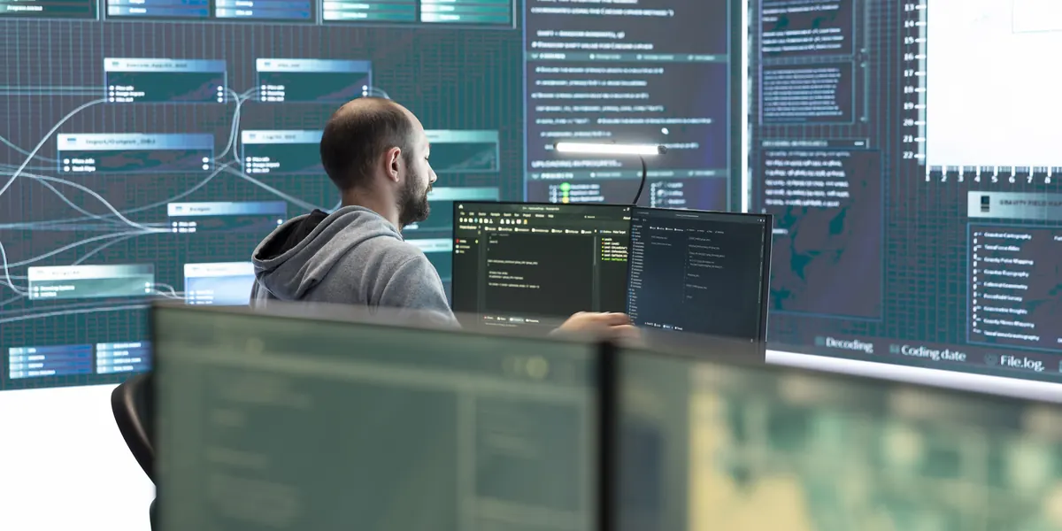 Especialista en informática que trabaja con varios monitores en los que se muestran datos del sistema