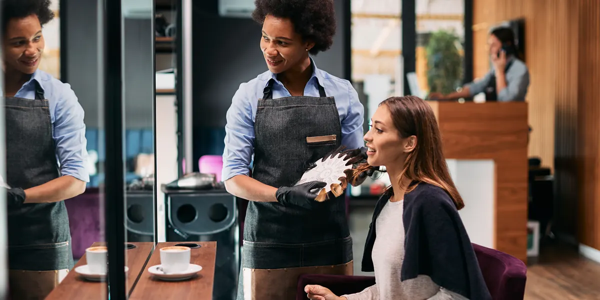 Una clienta de una peluquería eligiendo un color de pelo con un estilista