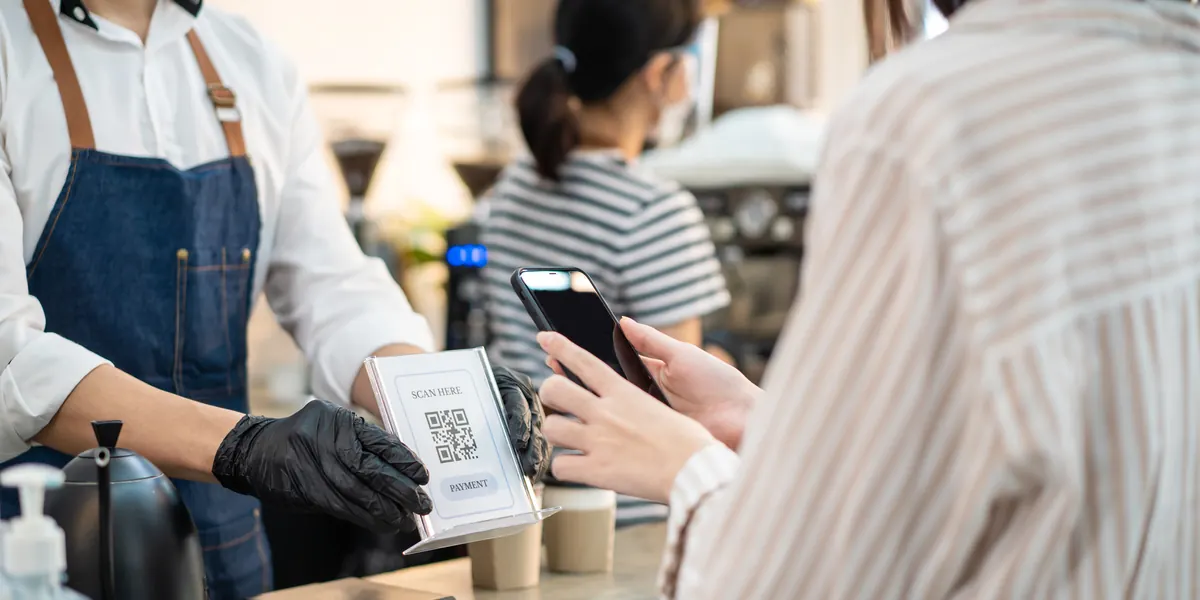 Un cliente que paga con un smartphone escaneando un código QR en una cafetería