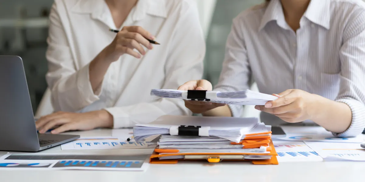 Dos profesionales comparando documentos en un escritorio