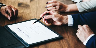 Business professionals reviewing and signing documents related to B2G e-invoicing and public sector compliance in Lithuania.