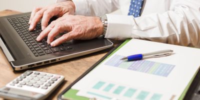 Professional calculating VAT data and preparing digital tax reporting in Germany using a laptop and financial documents
