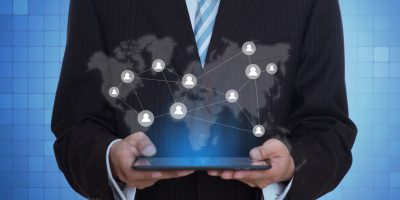 Business professional using tablet with global network hologram representing FacturaE digital invoicing