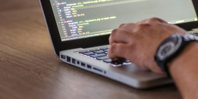 Desarrollador de código en ordenador portátil que representa la integración de la facturación electrónica KSeF y el cumplimiento de las obligaciones fiscales en Polonia