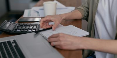 Person taking notes with notebook and laptop representing FacturaE electronic invoicing questions