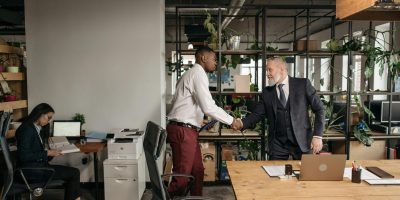 Two professionals closing a business deal with handshake representing compliance and regulatory collaboration