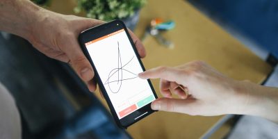 Person signing digitally on smartphone representing electronic signature under Ley Crea y Crece in Spain