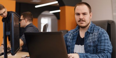 Software developer programming on desktop computer with code on screen