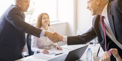 Business professionals shaking hands during a meeting to discuss digital transformation and compliance initiatives.