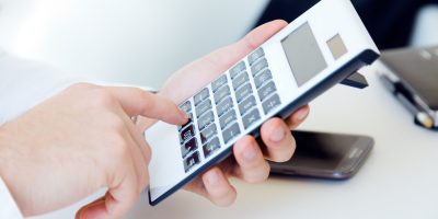 Person using a calculator representing SAF-T financial reporting and tax compliance processes in Poland